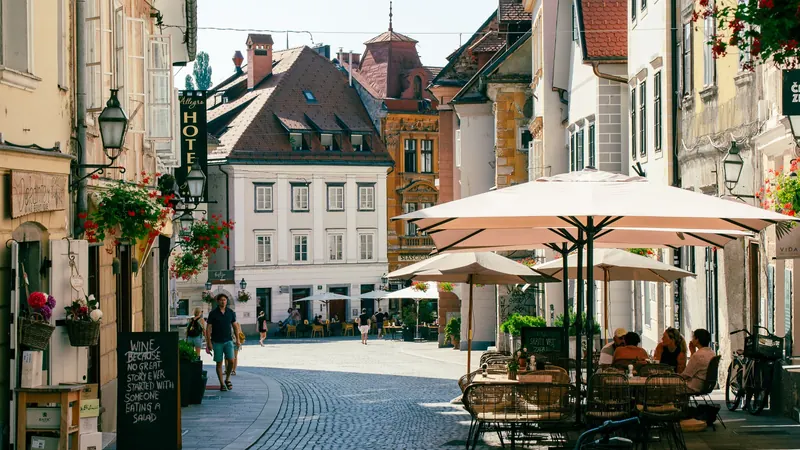 A street in the old town of Ljubljana at cafe-table height, awnings and shopfronts along one side
